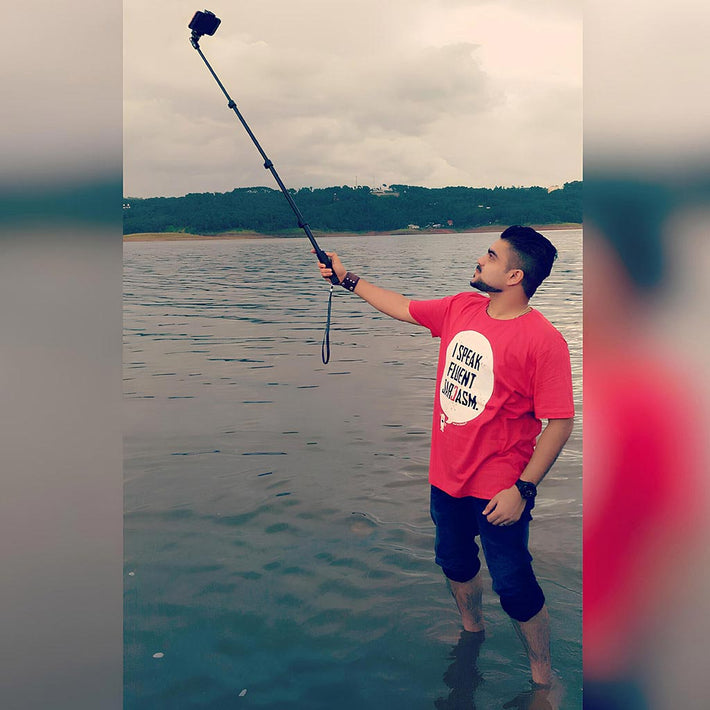 Man taking a selfie with a lake and greenery in the background and wearing WYO custom t-shirt