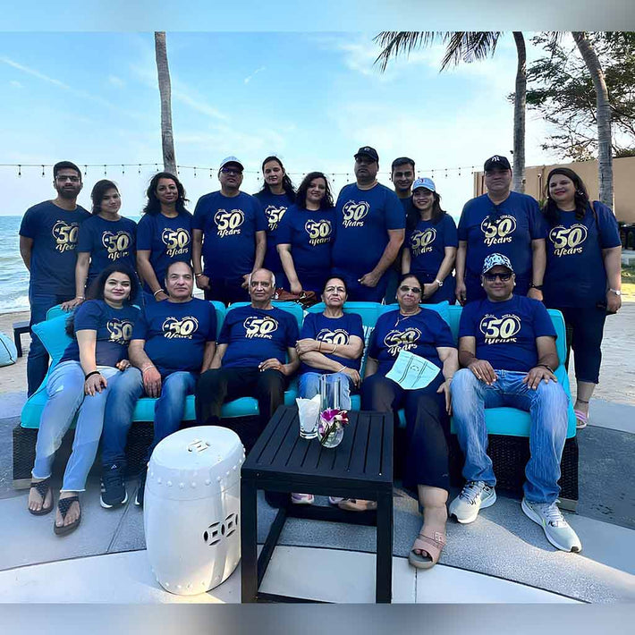 Group of people wearing matching blue shirts with '50' on a beach by WYO
