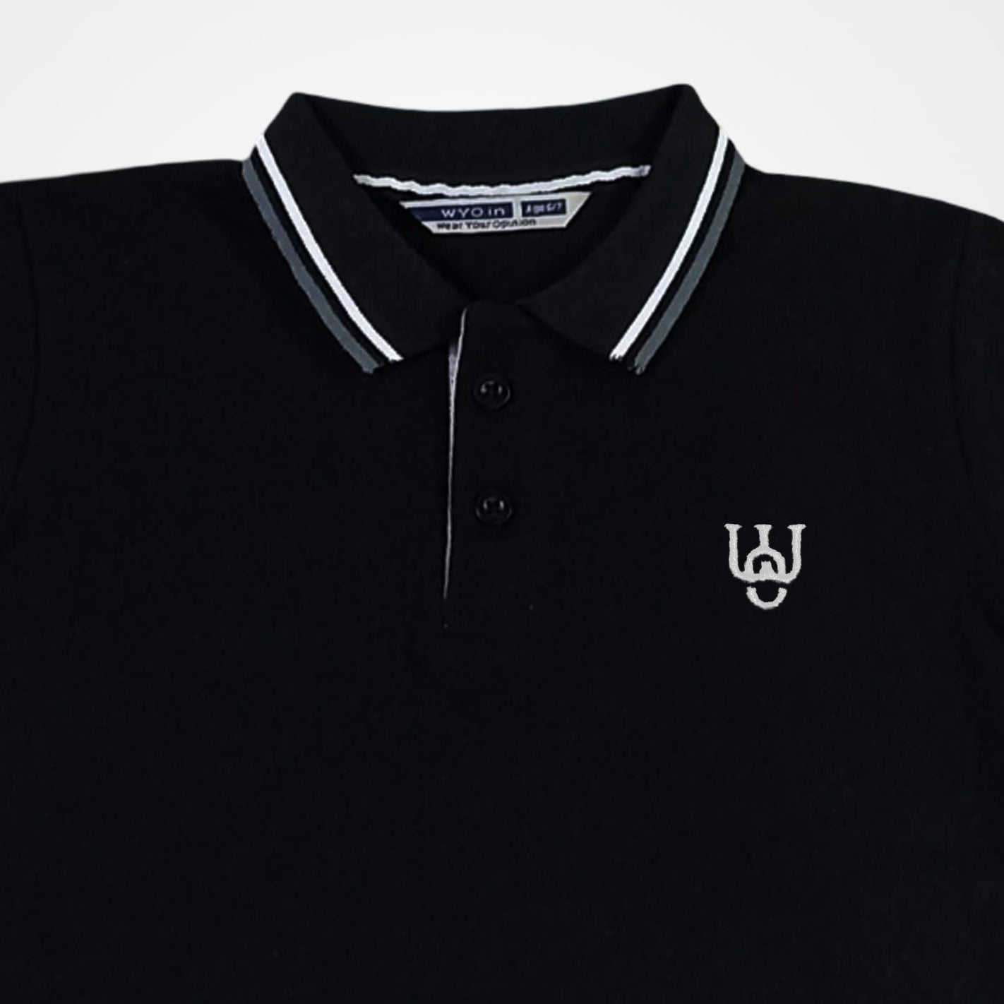 Close view of a WYO Black polo shirt with white collar and logo on a light gray background