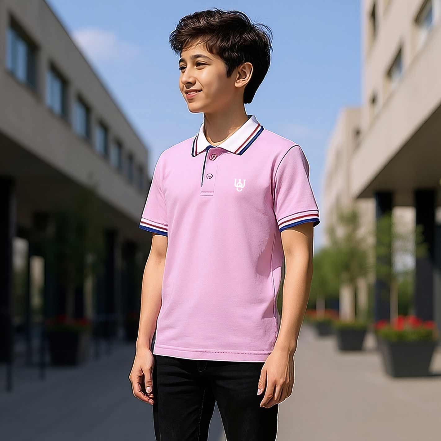 Kid wearing a WYO pink polo shirt with a building and blue sky in the background