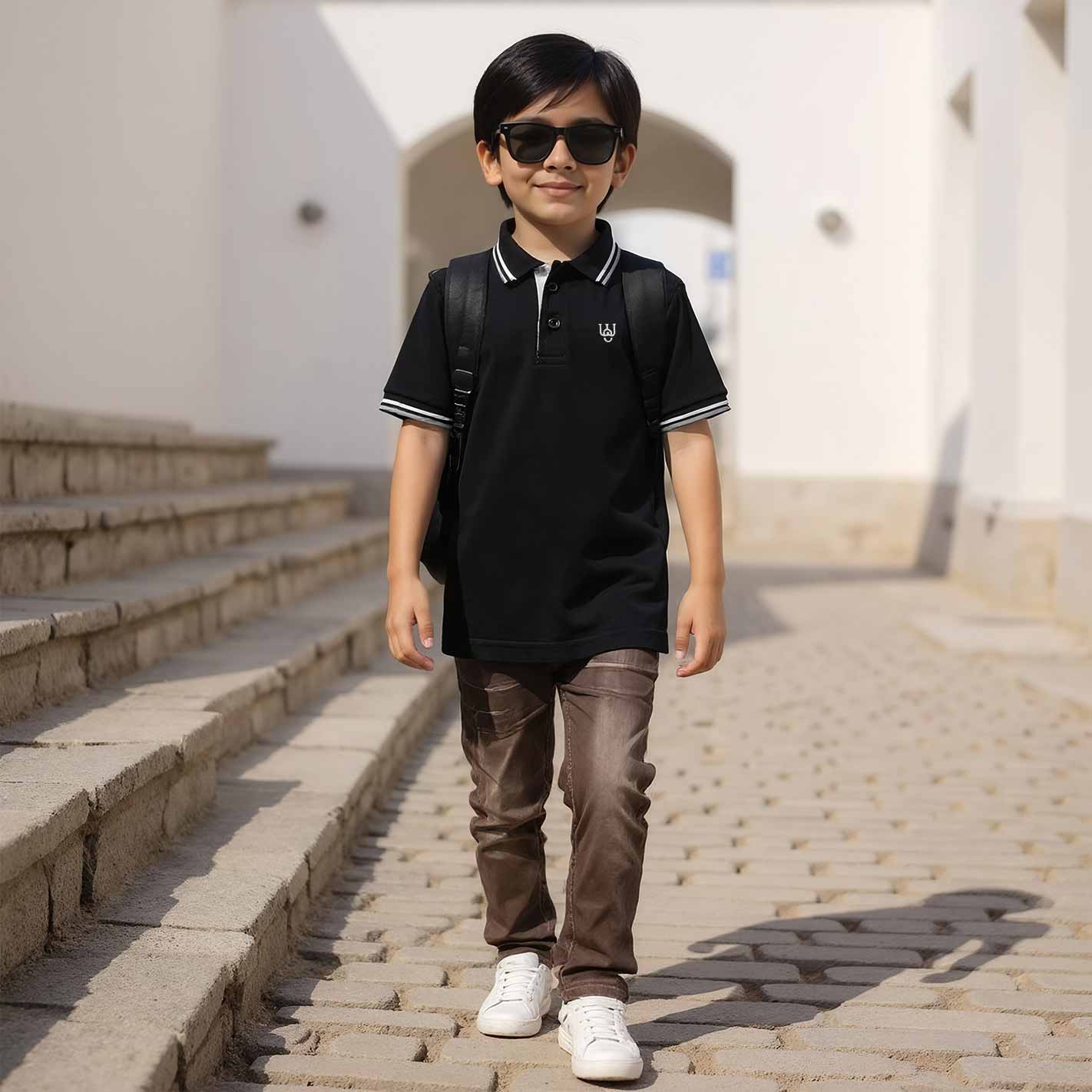 Kid wearing a WYO black polo shirt and sunglasses, standing on a stone pathway.