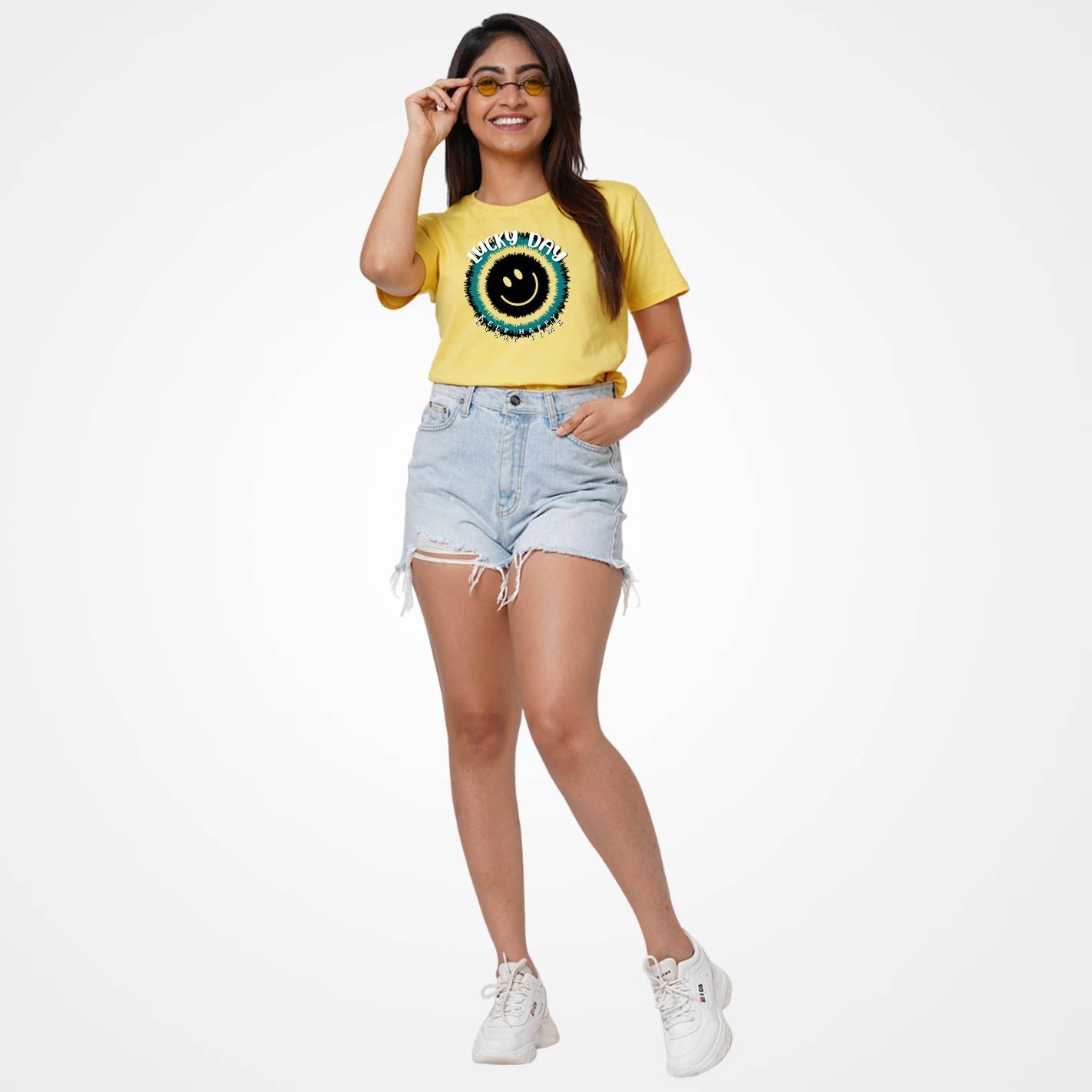 Woman wearing a WYO yellow t-shirt with a graphic design and denim shorts on a white background