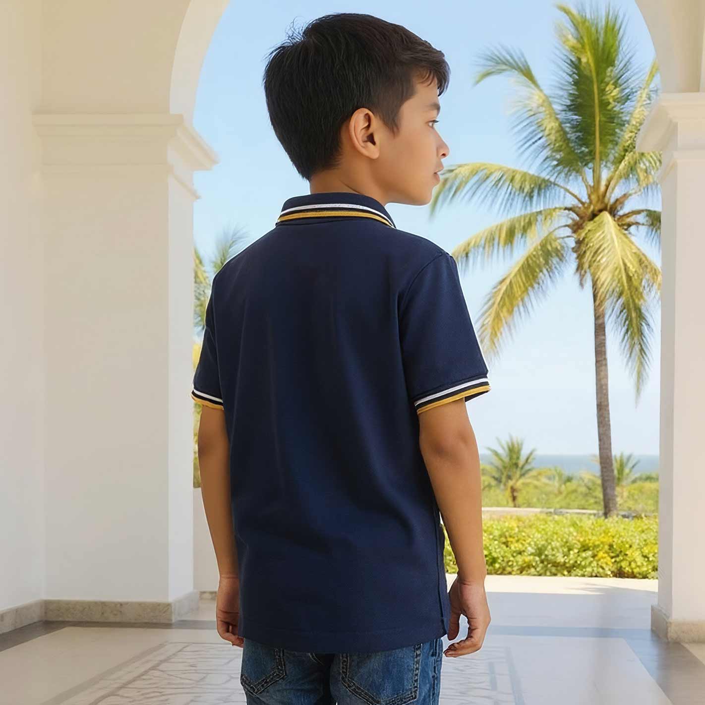 Back View of a Kid wearing a WYO navy blue polo shirt with yellow accents, standing in a tropical setting with palm trees.