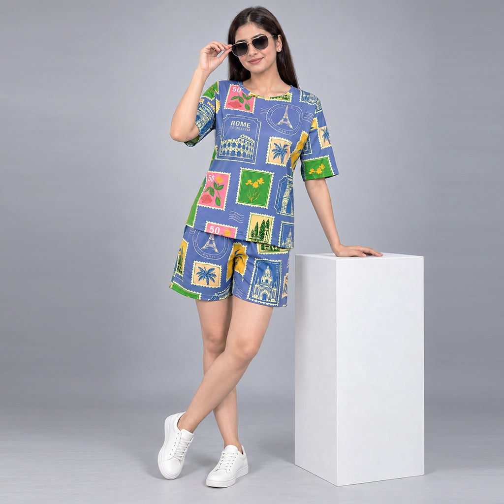 Woman modeling the WYO Travel Tales co-ord set: a blue travel-stamp print top and matching shorts.